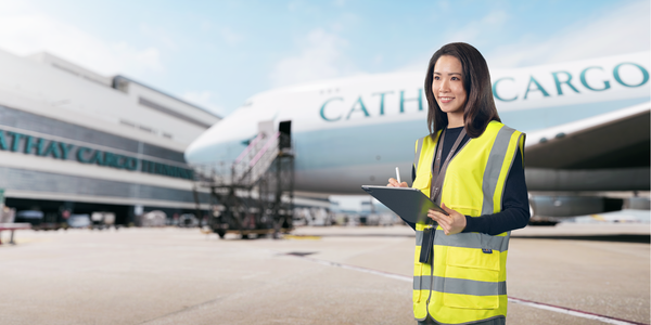 a cargo trainee standing in front of a cargo aircraft, holding a pen and paper