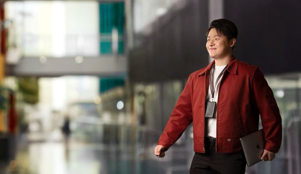 一位年轻专业人士，面带微笑，神情专注，手持笔记本电脑。