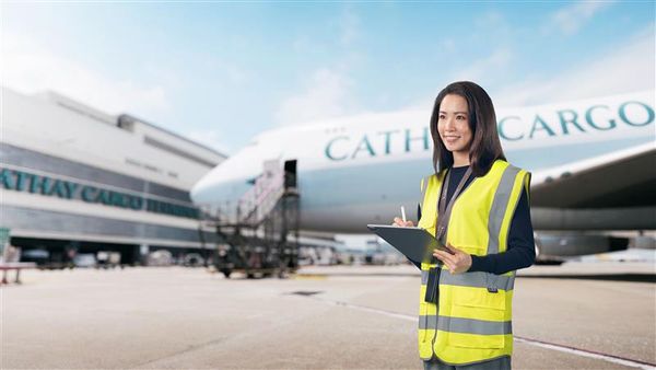 穿着黄色高能见度背心的人在“CATHAY CARGO”飞机前拿着剪贴板和笔。