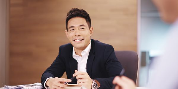 一位穿着西装的男子微笑地坐在桌旁。