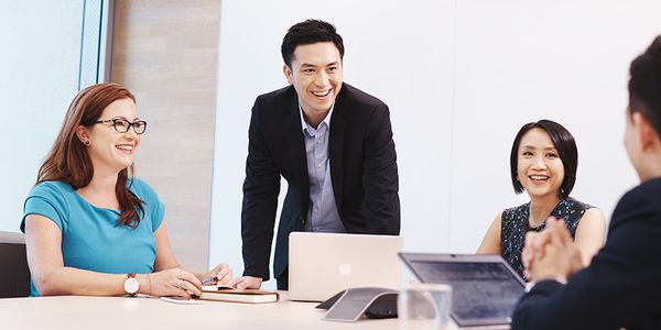 四名专业人士,包括2位男性和2位女性在充满自然光的会议室中讨论,桌上有笔记型电脑。
