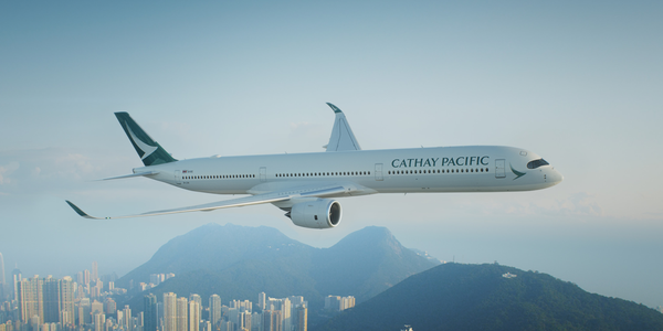 A Cathay Pacific aircraft flying over the Hong Kong landscape.