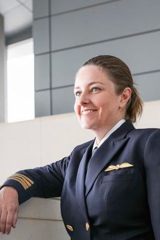 A smiling Captain wearing a flight uniform, showcasing confidence and professionalism.