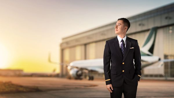 A pilot in Cathay Pacific uniform stands before an airplane